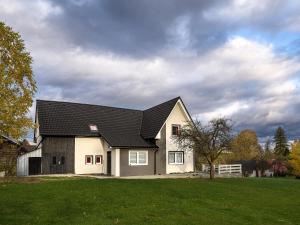 a white house with a black roof on a green field at Domeček Janov in Janov