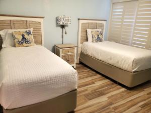 a bedroom with two beds and a night stand with a lamp at Jupiter Reef Club Resort in Jupiter