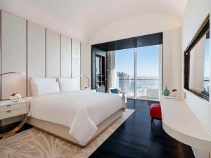ein Schlafzimmer mit einem großen weißen Bett und einem großen Fenster in der Unterkunft Fairmont Doha in Doha + 37 Fotos