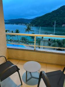 a balcony with chairs and a table and a view of the ocean at Loft 326 - APTO E VISTA ESPETACULARES in Mangaratiba