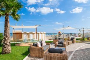 a patio with wicker chairs and tables and a beach at Hotel Mexico in Bellaria-Igea Marina