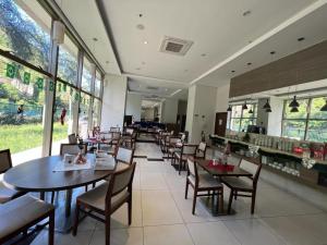 a dining room with tables and chairs and windows at Suíte com varanda em Via Premiere - Rio centro in Rio de Janeiro