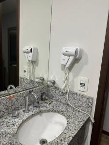 a bathroom sink with two hair dryers on a counter at Suíte com varanda em Via Premiere - Rio centro in Rio de Janeiro +5 photos