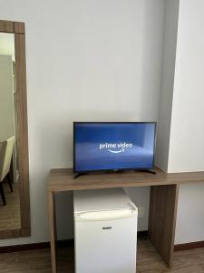 a tv sitting on top of a wooden table at Suíte com varanda em Via Premiere - Rio centro in Rio de Janeiro