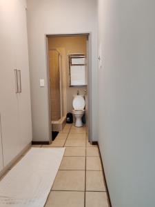 uma casa de banho com um WC, um chuveiro e piso em azulejo. em Tevin Nest em Sandton