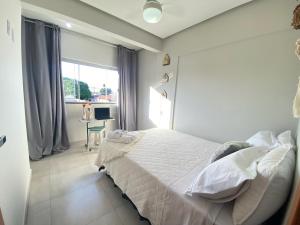 um quarto com uma cama branca e uma secretária em Oasis Urbano em Goiânia