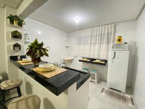 uma cozinha com um balcão preto e um frigorífico em Oasis Urbano em Goiânia