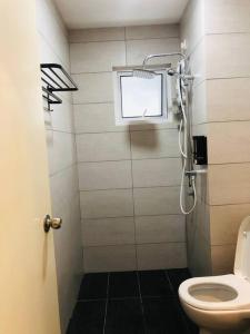 a bathroom with a shower with a toilet and a window at The Maisonnette Homestay in Kajang