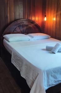 duże łóżko z białą pościelą i poduszkami w obiekcie Ribeirinhos Hostel w mieście Maués