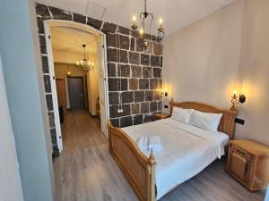1 dormitorio con cama y pared de ladrillo en Aratta Royal Hotel en Gyumri