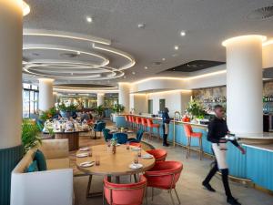 a restaurant with tables and chairs and people walking in it at Executive Suite at Ellipse in Waterfall Midrand in Midrand