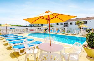 a pool with chairs and a table with an umbrella at 3 Europa Court, in Mawgan Porth