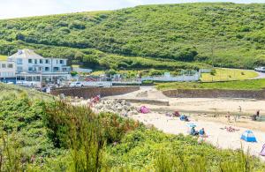 a group of people on a beach in front of a building at 3 Europa Court, in Mawgan Porth