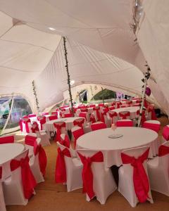 una carpa con mesas blancas y sillas rojas en The White Lion Inn en Brinklow