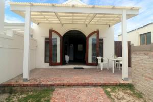 a white house with a patio with a table at M & M Flat Arniston in Arniston