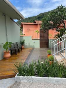 una terraza de madera con un banco en una casa en Moradas da Bibi, en Guarda do Embaú