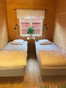 dwa łóżka w pokoju z oknem w obiekcie Markusfolks Gård w mieście Torsby