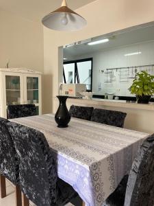 uma sala de jantar com uma mesa com um vaso sobre ela em Apartamento amplo a menos de 400 metros da praia localizado próximo a praça da Brunella, área nobre do Guarujá. no Guarujá