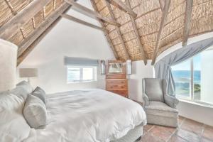 Un dormitorio con una cama y una silla y ventanas. en Longship In Arniston, en Arniston