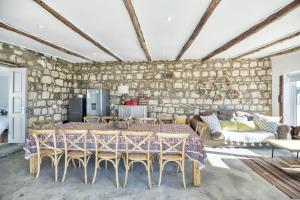 Una sala de estar con una pared de piedra y una mesa y sillas. en Longship In Arniston, en Arniston 45 fotos más