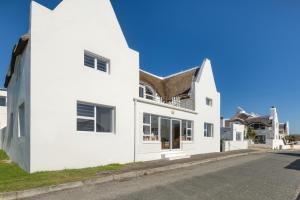 una casa blanca con techo marrón en Longship In Arniston, en Arniston