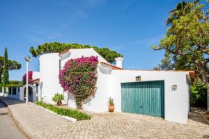 a white house with a green door and flowers at Villa Quadradinhos 38Q - great 4BR Vale do Lobo villa with AC Private Pool in Vale do Lobo