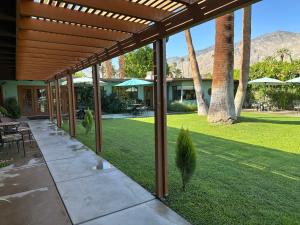 a covered patio with a lawn with a palm tree at Vista Grande Resort - A Gay Men's Resort in Palm Springs