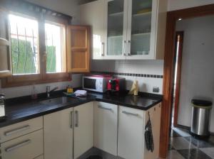 eine Küche mit weißen Schränken und einer Mikrowelle in der Unterkunft Villa Regina in Els Poblets in Els Poblets