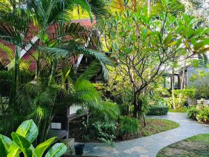 a garden with palm trees and a building at Niwas Ayutthaya in Phra Nakhon Si Ayutthaya