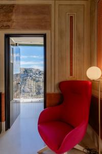 una silla roja en una habitación con ventana en Quarry Resort, en Matera