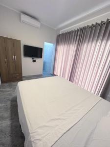 a bedroom with a large white bed and a television at la casa del encanto in Tarapoto