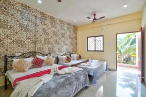 a bedroom with two beds and a wall with wallpaper at Abbi's Nest Beach House Goa in Calangute