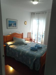 een slaapkamer met een bed met blauwe lakens en een raam bij Artmony piso centro del pueblo vista frente al mar appartement plein centre en front de mer in Port de la Selva