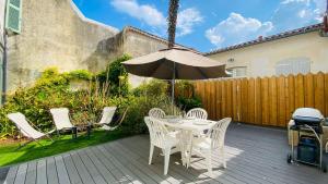a patio with a table and chairs and an umbrella at Superbe appartement en plein centre village in Saint-Martin-de-Ré