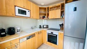 a kitchen with wooden cabinets and a stainless steel refrigerator at Superbe appartement en plein centre village in Saint-Martin-de-Ré