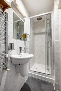 uma casa de banho branca com um lavatório e um chuveiro em Gorgeous One Bed in the Heart of Central London em Londres