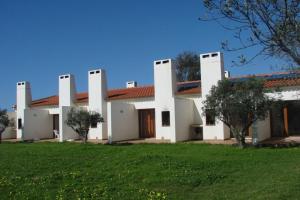 una gran casa blanca con un patio verde en Parque de Campismo da Ilha do Pessegueiro, en Porto Covo