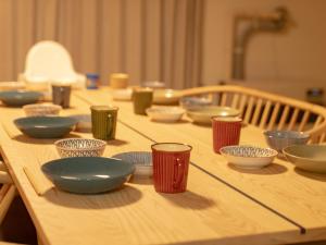 a long wooden table with bowls and plates on it at かんたろうもねたろうの母家 in Furano