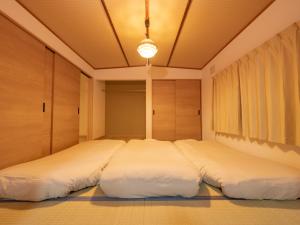 two large beds in a room with wooden cabinets at かんたろうもねたろうの母家 in Furano