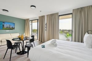 Habitación de hotel con cama, mesa y sillas en All Suites Paris Ouest Colombes, en Colombes