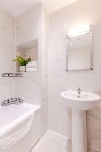 a white bathroom with a sink and a bath tub at Boutique Vertigo Apartment Central Kingston/London in Kingston upon Thames +7 photos