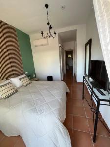 a bedroom with a white bed and a flat screen tv at Apto. Residencial La Alcaidesa in Alcaidesa