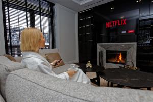 a woman sitting on a couch in a living room with a fireplace at Cristal Garden Chalet in Bukovel
