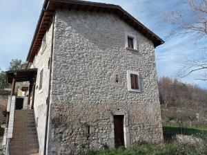 un grande edificio in pietra con due finestre e una scala di Famiglia nel vento a Caramanico Terme