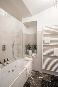 La salle de bains blanche est pourvue d'une baignoire et d'une plante. dans l'établissement Château GrandClément Piscine et Parc, à Villeurbanne