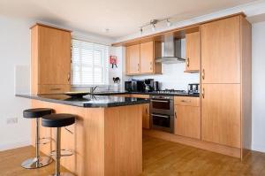 une cuisine avec des placards en bois et un comptoir noir dans l'établissement 8 Spinnakers, à Newquay