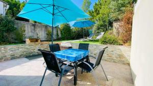 einen Tisch und Stühle mit einem blauen Tisch und Sonnenschirmen in der Unterkunft Villa récente avec accès à la plage par chemin à l'arrière de la maison in Le Bois-Plage-en-Ré
