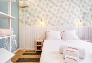 - une chambre avec un lit blanc et un mur à motifs dans l'établissement Hopstays Oporto Vibes - City Center Studio, à Porto