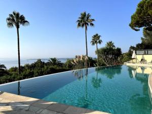 a large swimming pool with palm trees and the ocean at Super Cannes appartement 40m2, piscines tennis in Vallauris