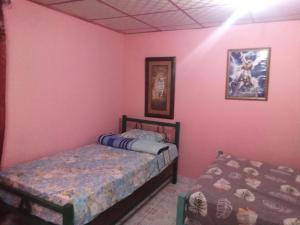 2 camas en una habitación con paredes rosas en Beautiful villa for singles, couples, families and groups cozy stay, en La Chorrera